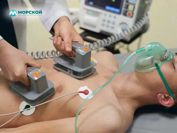 Мужчина лежит с микротоками подключенными к телу Врач устанавливает микротоки на теле пациенте